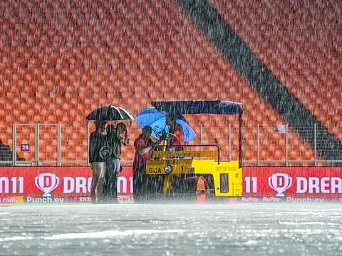 Ground staff take shelter under umbrellas as rain delays the start of the Indian Premier League (IPL) Twenty20 cricket match between Gujarat Titans and Kolkata Knight Riders at the Narendra Modi Stadium in Ahmedabad on Monday.