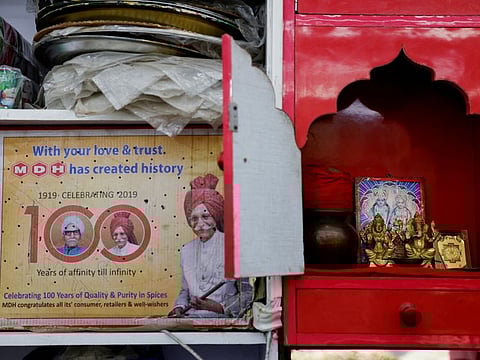 A carton displaying the Indian spice manufacturing company MDH's centenary celebration is placed next to a home temple at a shop in the old quarters of Delhi.