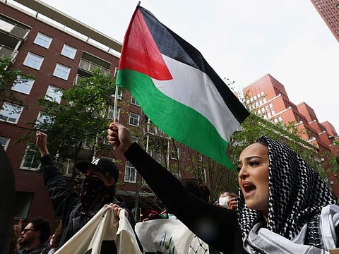 A woman holds up a Palestinian flag during a pro-Palestinian demonstration outside Leiden University, in The Hague Netherlands May 16, 2024, on the day of a hearing where South Africa requests new emergency measures over Israel's attacks on Rafah.