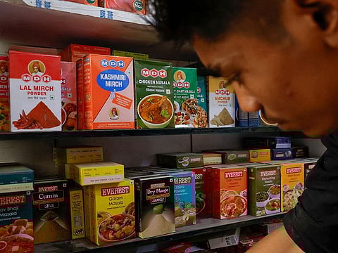 A man stands near the spice boxes of MDH and Everest kept on the shelf of a shop at a market in New Delhi, India.