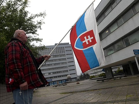 A supporter of the Slovakian government holds a Slovakian flag as he stands on May 17, 2024 in front of the hospital in Banska Bystrica, Slovakia where Slovak Prime Minister Robert Fico is being treated after he was shot "multiple times" the day before.