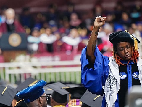 A Morehouse College faculty member stands and faces away from the stage in protest of the Israel-Hamas war as US President Joe Biden speaks at the Morehouse College Commencement on May 19, 2024 in Atlanta, Georgia.
