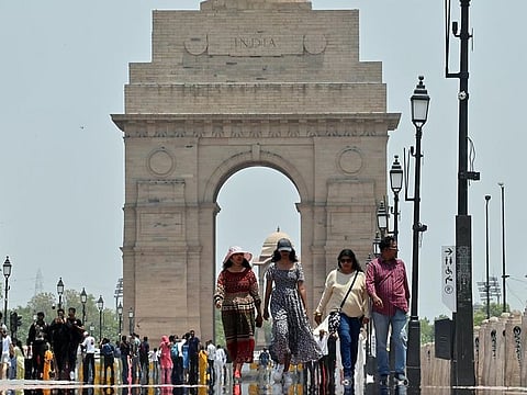 People walk on Kartavya Path while covering themselves to protect from the scorching heat on a hot summer day, in New Delhi on Monday.