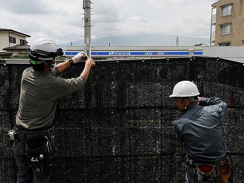 Workers erect a barrier to block the view of a popular Mount Fuji photo spot, near a convenience store in Fujikawaguchiko town, Yamanashi prefecture, Japan, on May 21, 2024.