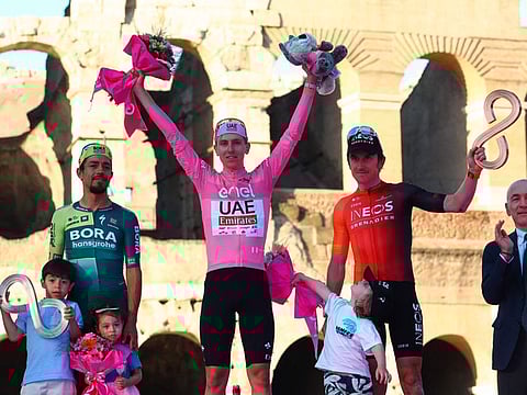 Team UAE's Slovenian rider Tadej Pogacar celebrates his overall leader's pink jersey on the podium in front of the Colosseum, flanked by overall second-placed Team Bora's Colombian rider Daniel Martinez (L) and overall third-placed Team Ineos' British rider Geraint Thomas (R) after the 21st and last stage of the 107th Giro d'Italia cycling race, 125km from Rome to Rome on Sunday.