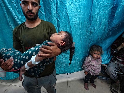 A man carries a girl injured in Israeli strikes on Bureij, at the Al Aqsa Martyrs Hospital in Deir Al Balah in the central Gaza Strip.