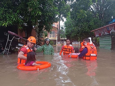 Children are evacuated from a flooded area by coast guard personnel in Lucena, Quezon Province.