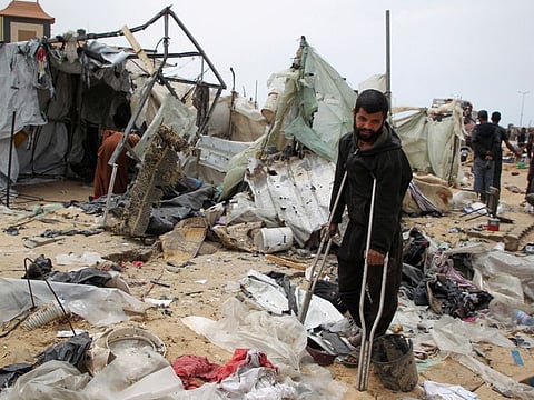A man looks on as Palestinians inspect a tent camp damaged in an Israeli strike during an Israeli military operation, in Rafah, in the southern Gaza Strip, May 28, 2024.