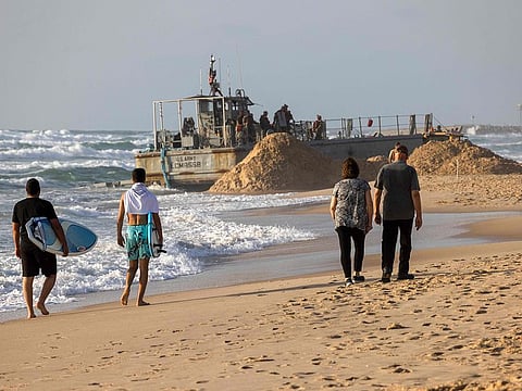 Israelis walk near a US Army vessel that ran aground at a beach in the coastal city of Ashdod on May 25, 2024. The US military said four of its vessels, supporting a temporary pier built to deliver aid to Gaza by sea, had run aground in heavy seas.