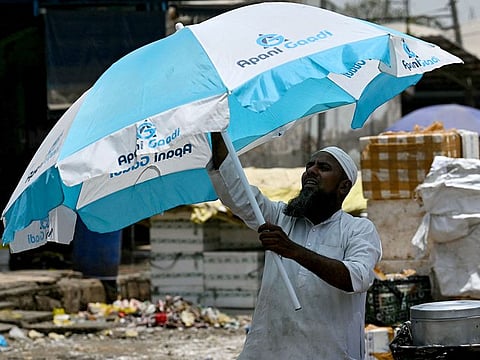 A man sets up his umbrella for shade on a hot summer afternoon in New Delhi.