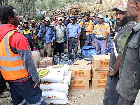 Relief workers gather around provisions to be distributed, in the aftermath of a landslide in Enga Province, Papua New Guinea.