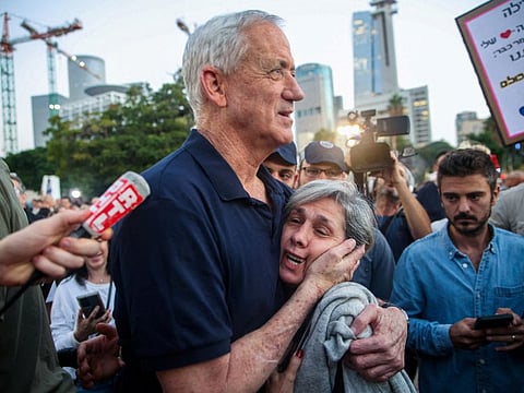 Israel war cabinet member Benny Gantz embraces a woman as he walks to meet with family members of hostages in Tel Aviv.
