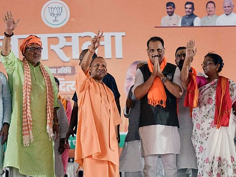 Uttar Pradesh Chief Minister Yogi Adityanath and BJP candidate for Saran, Rajiv Pratap Rudy greet people during a public meeting for the Lok Sabha elections, in Saran on Friday.