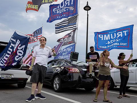 Supporters hold placards and flags following the announcement of the verdict in former US President Donald Trump's criminal trial over charges that he falsified business records to conceal money paid to silence porn star Stormy Daniels in 2016, outside Trump’s Mar-a-Lago resort in Palm Beach, Florida, on May 30, 2024.