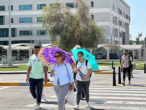 Residents walk with umbrella during hot summer in Abu Dhabi