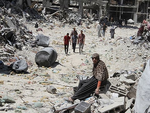 A woman rests on rubble, as Palestinians inspect the damage after Israeli forces withdrew from Jabalia refugee camp, following a raid, in the northern Gaza Strip, May 31, 2024.