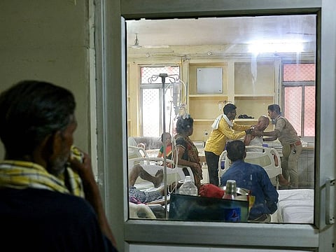 People watch as a patient suffering from heat stroke is helped to get up inside an emergency room in a government hospital during a severe heatwave in Varanasi.