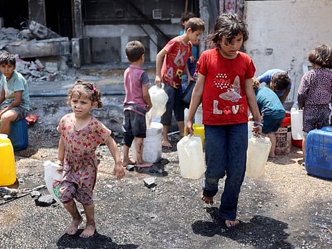 Palestinian children fill plastic containers with water in the grounds of a partially destroyed school being used as a shelter in the Jabalia refugee camp, in the northern Gaza Strip on June 3, 2024.