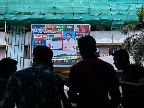 Pedestrians watch share prices on a digital broadcast outside the Bombay Stock Exchange (BSE) on the day of India's general election result in Mumbai .