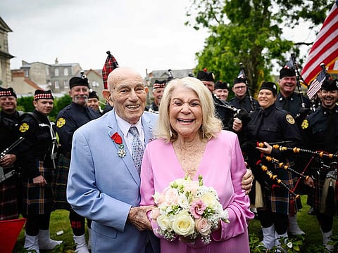 Newly-weds Jeanne Swerlin, 96, (R) and US WWII veteran Harold Terens, 100, (L) pose for photographs in front of a piper band as they celebrate their marriage during a wedding at the town hall of Carentan-les-Marais, in Normandy, northwestern France, on June 8, 2024.