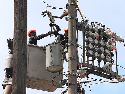 Manila Electric Co (Meralco) linemen repair power meters atop electricity post at the port area of Metro Manila, Philippines.