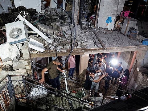 People walk in a damaged building targeted by Israeli forces during a raid in Kafr Dan, near Jenin, in West Bank, on June 11, 2024.