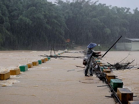 A villager clears tree branches stuck on the bridge in the rain at a flooded area in Liuzhou, in southwestern China's Guangxi province.