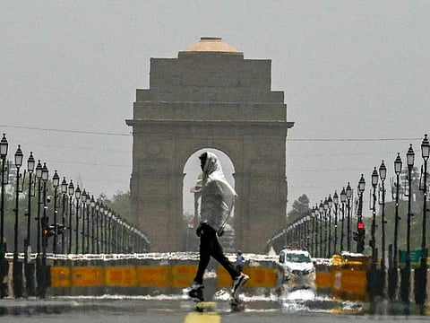 A man wears a scarf as he walks past the India Gate during an intense heatwave in New Delhi on June 18, 2024