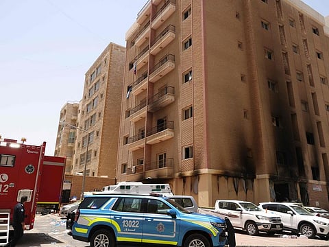 Kuwaiti firefighters and security forces gather outside a building which was ingulfed by fire, in Kuwait City, on June 12.
