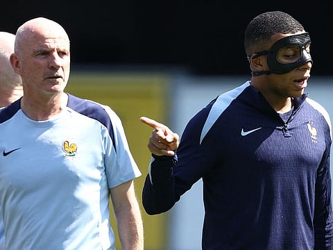France's forward Kylian Mbappe, wearing a protective mask, takes part in a training session next to French assistant coach Guy Stephan on the eve of their Uefa Euro 2024 Group D match against Poland.