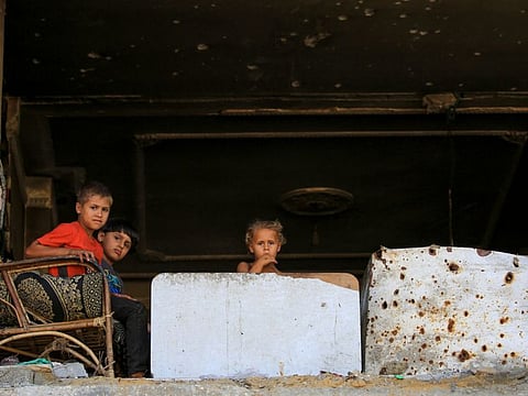 Children look on from inside a building that was damaged during Israeli bombardment, Al Bureij refugee camp in the central Gaza Strip on June 24, 2024.