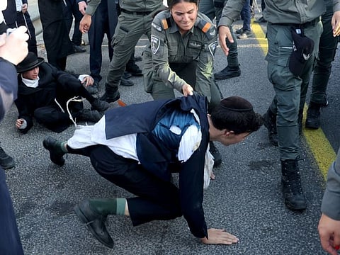 Israeli police grapple with a protester as they they try to disperse Ultra-Orthodox Jews blocking a highway during a protest against possible changes regarding the laws on the military draft from which the Ultra-Orthodox community has traditionally been exempt, in the central Israeli city of Bnei Brak, on June 20, 2024.