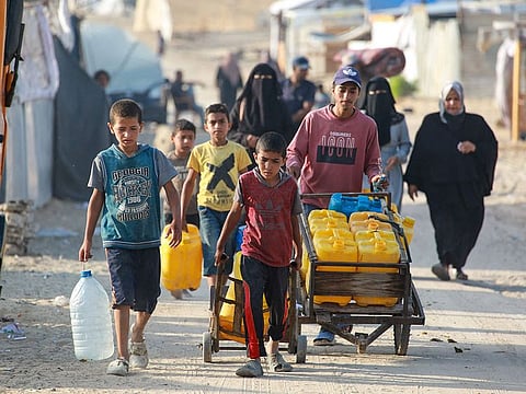 Palestinians transport water containers in a displacement camp in the Al Mawasi area in Khan Yunis.