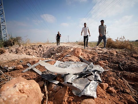 Palestinian men walk towards a crater and debris caused by an improvised explosive device which targeted an Israeli military jeep along a dirty used during their military operation, in the northern Palestinian city of Jenin, in the Israeli occupied West Bank on June 27, 2024.