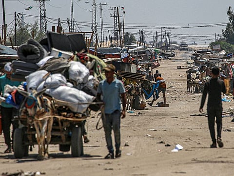 An Israeli tank takes position in the background as displaced Palestinians evacuate the Shakush area on the northwestern outskirts of Rafah, in the southern Gaza Strip, on June 28, 2024, amid the ongoing conflict between Israel and the militant Hamas group.