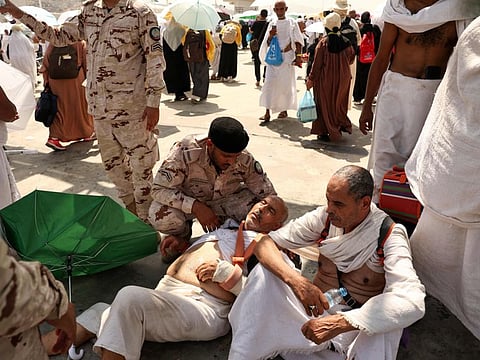 A man effected by the scorching heat is helped by a member of the Saudi security forces as pilgrims arrive to perform the symbolic 'stoning of the devil' ritual as part of the pilgrimage in Mina, near Mecca, on June 16, 2024.