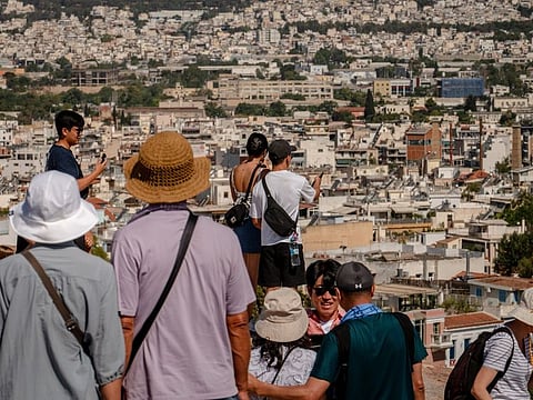 Tourists take photos outside the Acropolis ancient site in Athens, on June 28, 2024.
