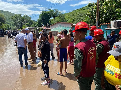 Residents and members of the People's Guard stand on a flooded street after a river swelled due to heavy rains following the passage of Hurricane Beryl on the road from Cumana to Cumanacoa, Sucre State, Venezuela.