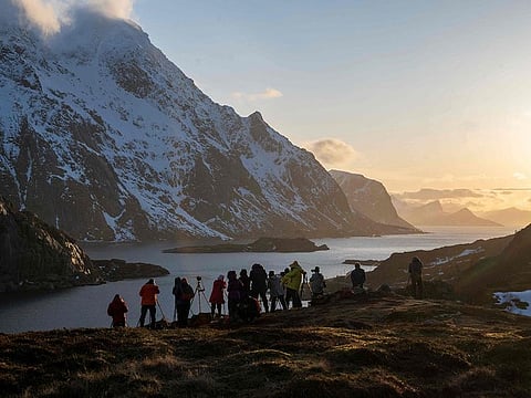 Tourists photograph a fjord in Unstad on Lofoten Islands.