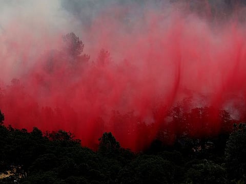 Phos-Chek fire retardant falls from a firefighter aircraft ahead of the Thompson Fire in Oroville, California.