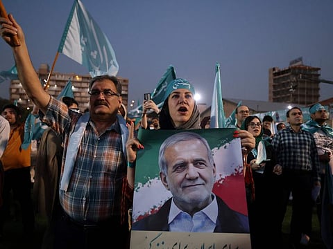 A woman holds a picture of Iranian reformist candidate Masoud Pezeshkian during a campaign rally, two days before a presidential election runoff following a first round marked by a historically low turnout, at a stadium in Tehran on July 3, 2024.