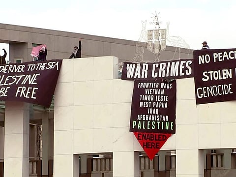 This frame grab taken from video footage provided by Australian Broadcast Corporation (ABC) on July 4, 2024, via AFPTV shows protesters with banners above the main entrance to Parliament House in Canberra.
