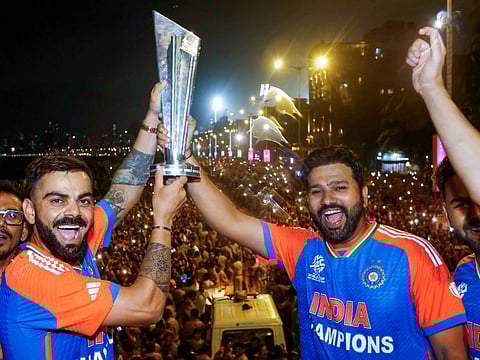 Indian captain Rohit Sharma and Virat Kohli flash the ICC T20 World Cup trophy to a huge crowd of fans during the victory parade, in Mumbai last Thursday.