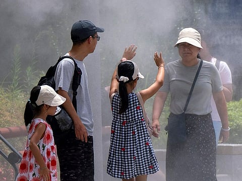 A family cools down under a mist shower during hot weather in central Tokyo on July 9, 2024.