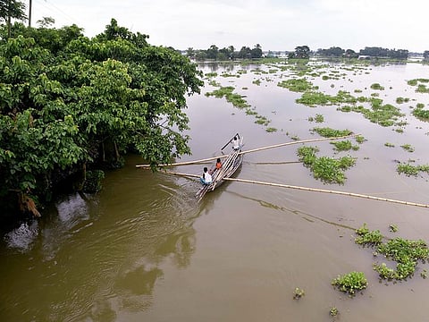 People use boats to travel through the flooded area after the water level of the Brahmaputra River rises following heavy rainfall, at Balimuk village in Morigaon.