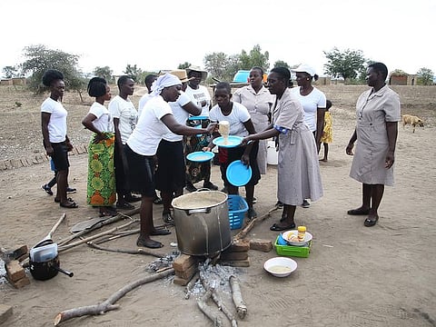 A brigade of nutrition peer educators dish into plates cupfulls of the prepared porridge formulation dubbed maworesa, which translates to the very best porridge, which is cooked with readily available ingredients that are locally sourced to prevent children from falling into malnutrition as the El-Nino induced drought, in Mudzi.