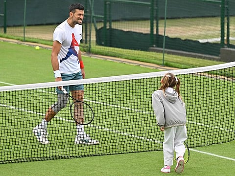 Serbia's Novak Djokovic interacts with his daughter on the Aorangi practice courts at The All England Lawn Tennis and Croquet Club in Wimbledon on Wednesday.