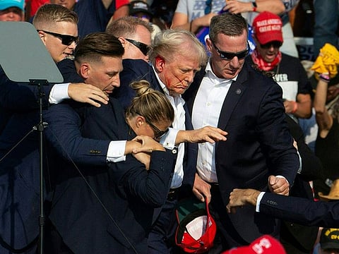 Republican candidate Donald Trump is seen with blood on his face surrounded by secret service agents as he is taken off the stage at a campaign event at Butler Farm Show Inc. in Butler, Pennsylvania.