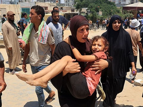 A Palestinian woman carries an injured child to the Nasser hospital in Khan Younis on July 13, 2024, one of the health establishments to which casualties were rushed after an Israeli strike killed at least 92 people and injured many others at the Al Mawasi camp for the war displaced in the south of the Palestinian territory, according to the Hamas-run health ministry.