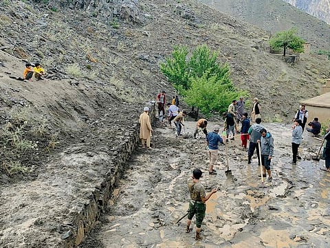 Afghan residents shovel mud following flash floods after heavy rainfall at Pesgaran village in Dara district, Panjshir province on July 15, 2024. At least 35 people were killed and 230 injured on July 15, after heavy rain in Afghanistan, a local official said
